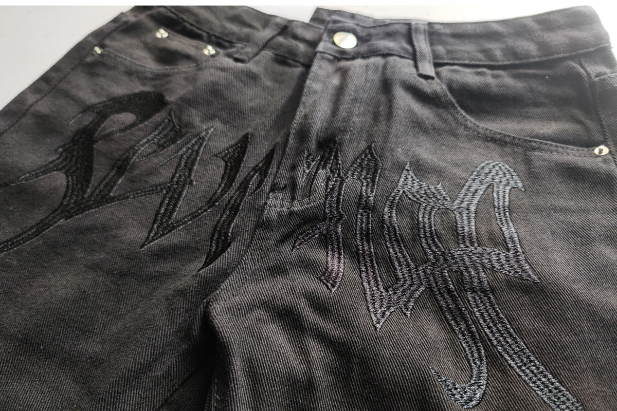 Edgy and modern baggy jeans with intricate black embroidery.